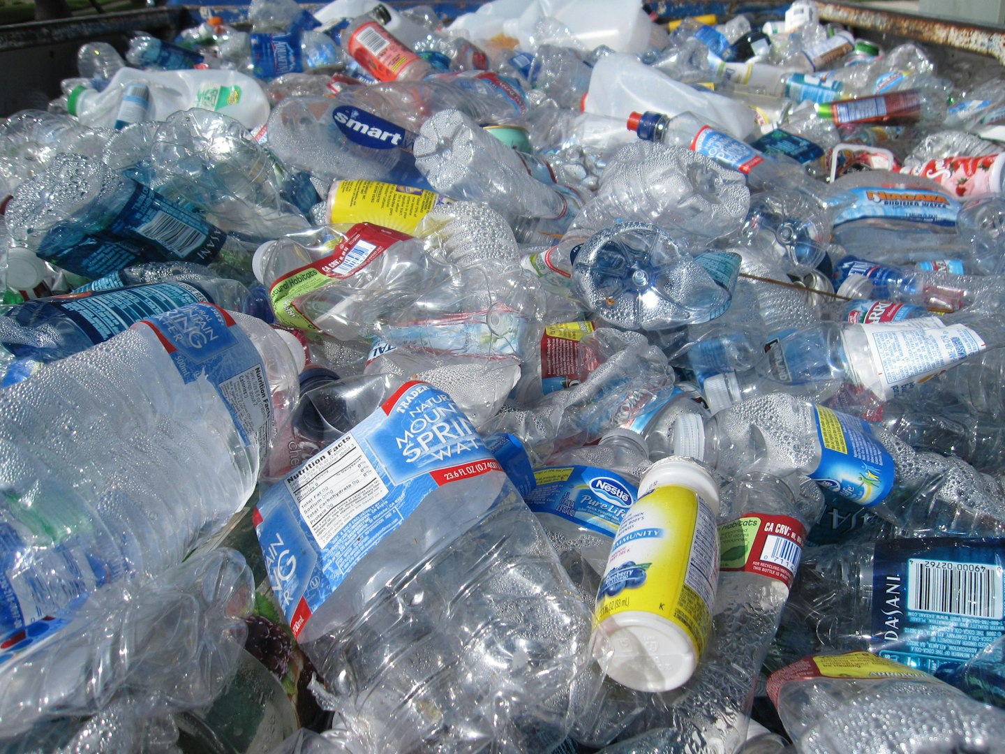 Hromada stlačených, použitých plastových fliaš, znázorňujúca plastový odpad a potrebu recyklácie.