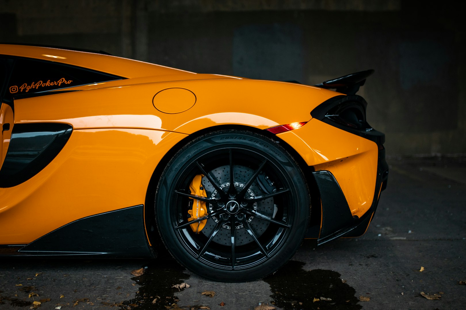 Zadná časť lesklého oranžového McLarenu 600LT s čistým diskom kolesa, ošetreného Nanowash technológiou.